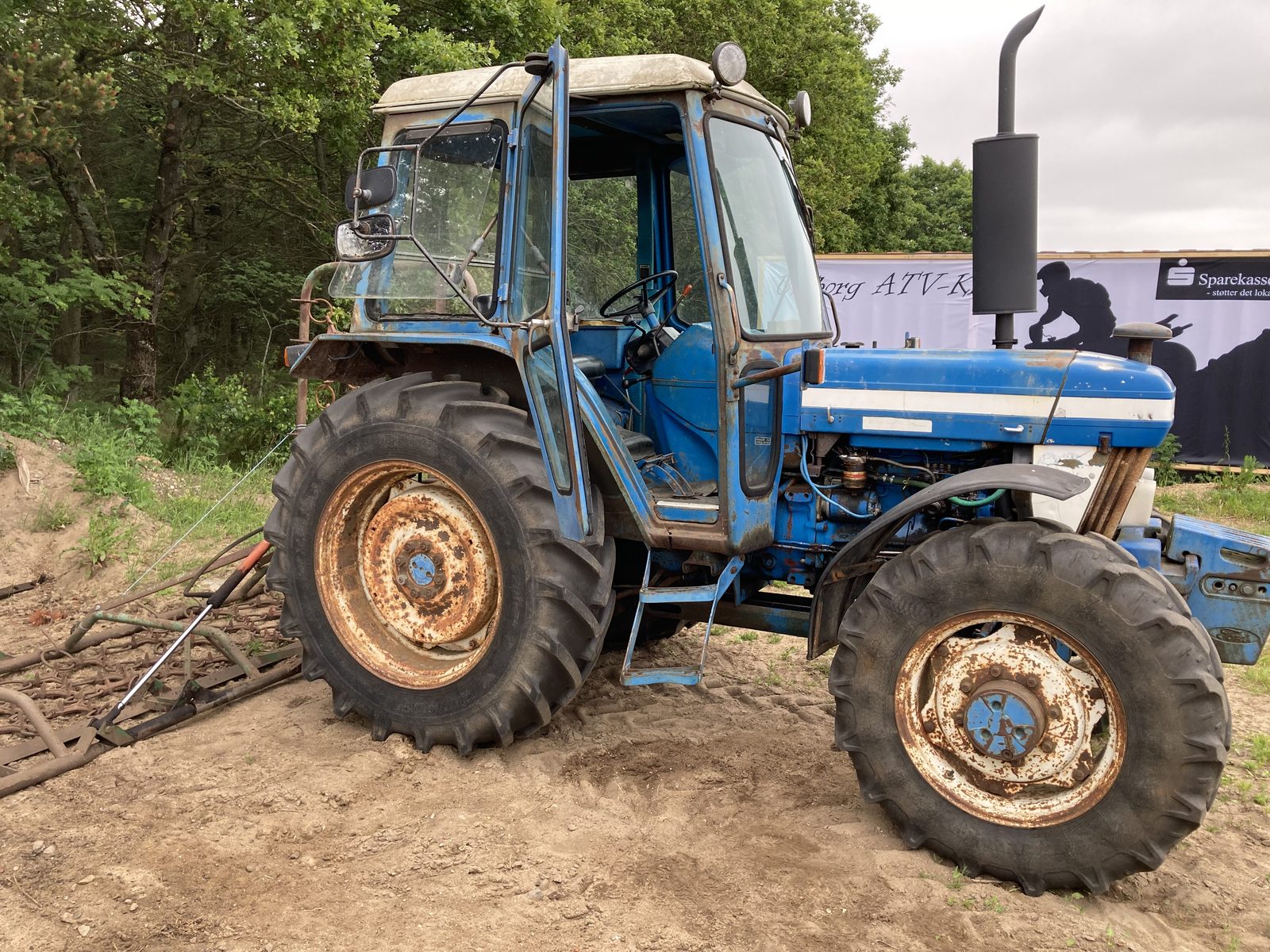 Blå Ford-traktor ved banen foran klubbens banner